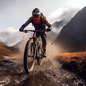 Mountain biker riding through a stream in a mountainous landscape