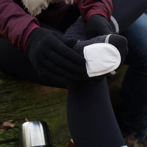Person applying a Hothands adhesive toe warmer to a sock