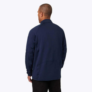 Back view of a man wearing a navy blue Mobile Warming long sleeve zip up jacket