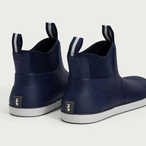 Rear view of navy blue Huk ankle boots with white soles and pull tabs