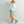Woman wearing Huk white long sleeve shirt and teal shorts with matching teal ankle boots