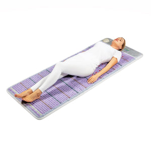 Woman lying on a purple and grey infrared therapy mat