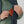 Person placing a brown leather Fjallraven wallet into the chest pocket of a green fleece vest