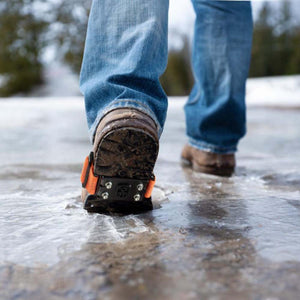 Impacto ice cleats attached to a boot walking on a frozen surface
