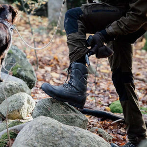 Arctic Volt black leather hiking boot on a rock in a forest