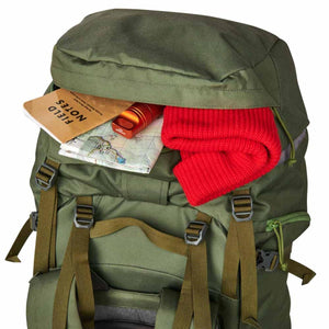 Kelty olive green backpack with open pocket containing a notebook map flashlight and red beanie
