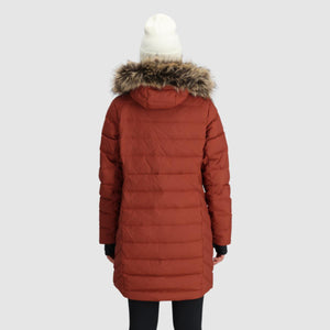 Back view of a person wearing an Outdoor Research rust colored hooded parka with faux fur trim and a white beanie
