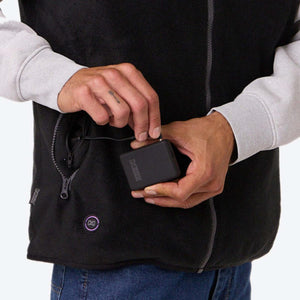 Person connecting a Mobile Warming battery pack to a heated vest pocket