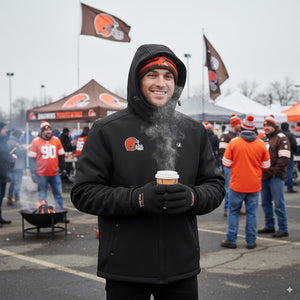Man wearing ActionHeat black heated jacket and gloves holding a steaming cup at a Cleveland Browns tailgate