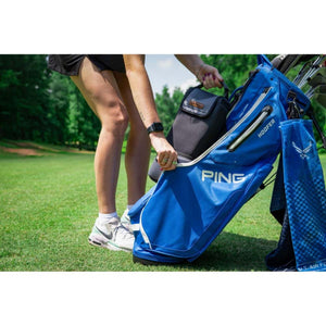 Golfer placing a black Kanga cooler bag into a blue Ping golf bag on a course