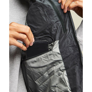 Person placing a smartphone into the interior chest pocket of a black jacket