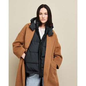 Model wearing a Kelvin brown wool coat layered over a black hooded puffer vest