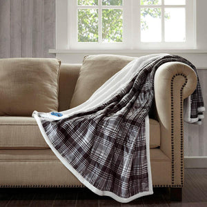 Woolrich plaid heated throw blanket with white sherpa lining draped over a beige sofa