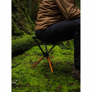 Person sitting on a Hillsound portable tripod stool in a mossy forest