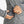 Close up of hand placing a black portable power bank into a zippered pocket of a grey marl athletic jacket
