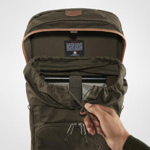 Hand pulling drawstring to open main compartment of dark green Fjallraven backpack