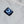 Close up of a square power button with a glowing blue V logo on grey fabric