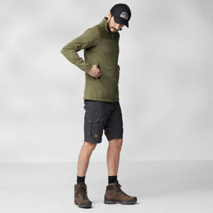 Man wearing FjallRaven olive green zip jacket black cap dark shorts and brown hiking boots