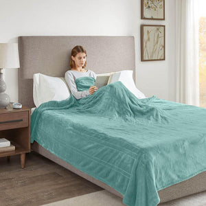 Beautyrest teal plush electric blanket draped over a person reading in bed