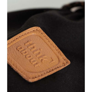 Tan leather patch with embossed think about text on black fabric