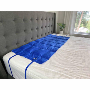 Blue quilted mattress topper with elastic straps secured on a bed
