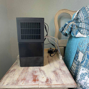 Mattress Cooler unit on a wooden nightstand next to a bed