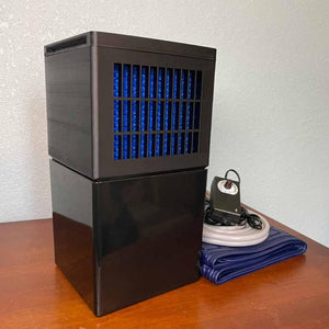 Mattress Cooler unit with power adapter and blue tubing on a wooden surface