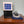 Black and white water cooling unit with a blue mattress pad and power adapter on a wooden surface
