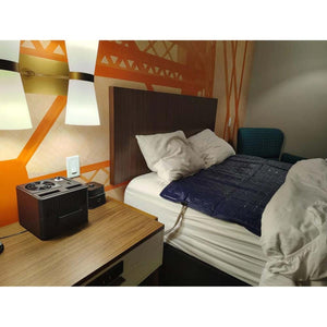 Mattress Cooler unit on a nightstand with a blue cooling pad on the bed
