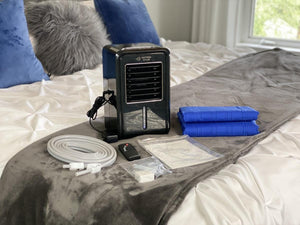 Mattress Cooler unit with cooling pads, hose, remote, and manual on a bed