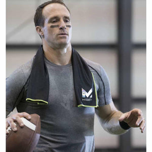 Athlete wearing a black Mission cooling towel around his neck while holding a football