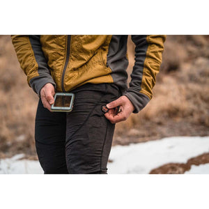 Person adjusting Mobile Warming heated pants control button while holding a smartphone