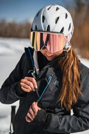 Person wearing a ski helmet and goggles putting a phone into a Fieldsheer jacket chest pocket