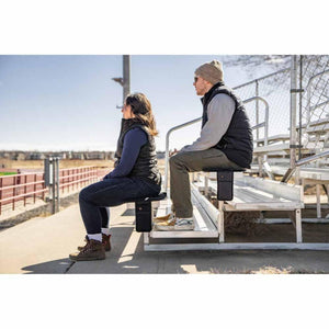 Two people sitting on Mobile Warming heated seat cushions on stadium bleachers