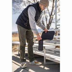 Person holding a Mobile Warming heated vest battery pack and case