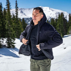 Man wearing a black Mobile Warming hooded jacket in a snowy mountain landscape