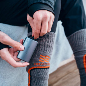 Person connecting a portable battery pack to a Fieldsheer heated sock