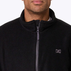 Close up of a black Mobile Warming fleece jacket with a front zipper