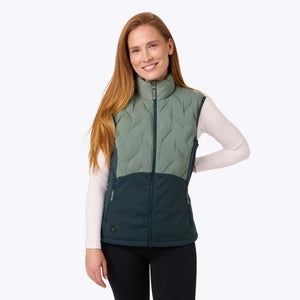 Woman wearing a two-tone green Mobile Warming heated vest over a white long-sleeve shirt