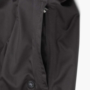 Mobile Warming black garment featuring a zippered pocket and a circular power button