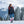 Woman wearing a black Mobile Warming heated jacket and red backpack walking in a snowy mountain landscape