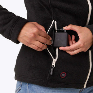 Hands connecting a battery pack into the pocket of a black Mobile Warming fleece jacket