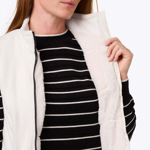 Mobile Warming white fleece vest with black zipper worn over a black and white striped sweater