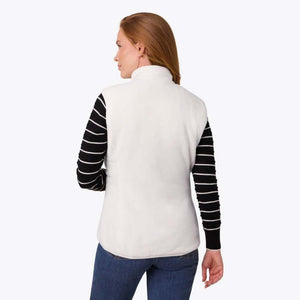Back view of a woman wearing a white Mobile Warming fleece vest over a black and white striped long sleeve shirt