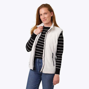 Woman wearing a white Mobile Warming fleece vest over a black and white striped long sleeve shirt and blue jeans