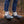 Person wearing Muck grey and light blue ankle boots standing on a log