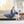 Woman reading a book while wrapped in a blue Beautyrest heated throw blanket on a beige sofa