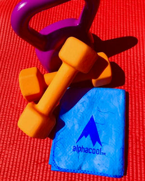 Purple kettlebell and orange dumbbells on a red mat with an Alphacool cooling towel