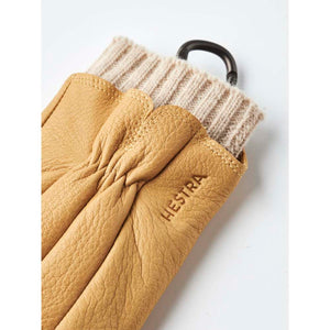 Tan leather Hestra glove with a ribbed knit cuff and black carabiner
