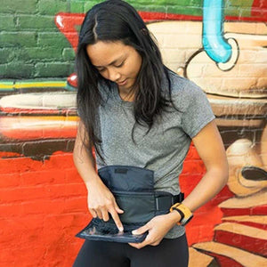 Person wearing a Nathan waist belt and interacting with a smartphone in the clear pouch